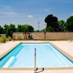 Claremont fiberglass inground swimming pool with rectangular form, built-in entry steps, and spacious stamped-concrete patio in a landscaped backyard