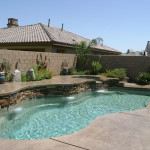 Laguna freeform inground fiberglass pool with curved organic shape, light concrete pool deck and landscaped backyard setting