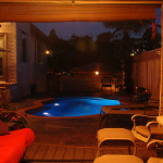 Laguna freeform inground fiberglass pool with lagoon-style curves, tan concrete deck and landscaped backyard seating area