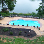 Laguna freeform inground fiberglass pool with smooth curved shape, concrete pool deck and landscaped backyard seating area
