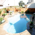 Laguna freeform inground fiberglass pool 59B with curved freeform shape, concrete pool deck and residential backyard setting