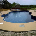 Laguna freeform inground fiberglass pool with smooth curved shape, tan concrete deck and open backyard countryside view