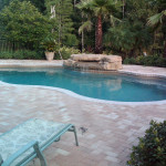 Laguna freeform inground fiberglass pool with curved freeform shape and concrete pool deck in a landscaped residential backyard