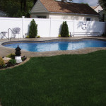 Laguna Freeform inground fiberglass pool with curved lagoon-style shape, built-in entry steps and textured concrete deck in a landscaped backyard