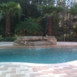 Laguna freeform inground fiberglass pool with lagoon-style curves, shallow entry steps and stamped concrete pool deck in a suburban backyard