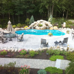 Laguna freeform inground fiberglass pool with smooth curved shape, tan concrete deck and minimal landscaping in a private backyard