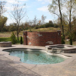 Laguna freeform inground fiberglass pool with smooth curved shape and surrounding concrete deck in a landscaped backyard
