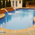 Laguna freeform inground fiberglass swimming pool with organic curved shape, built-in steps and spacious backyard lounging area